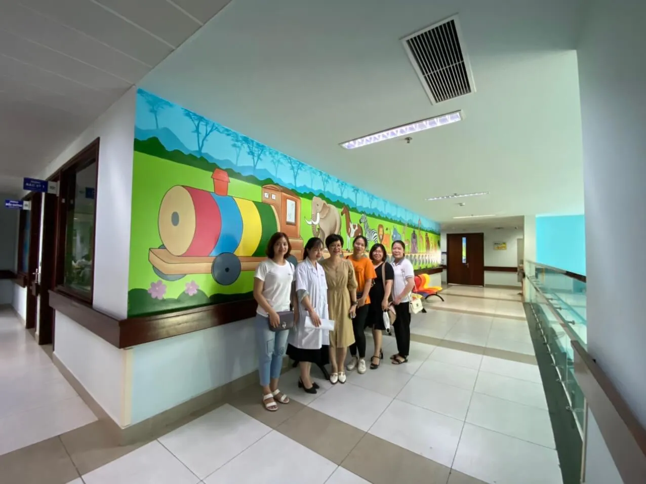Đoàn thiện nguyện chụp ảnh cùng y bác sĩ trước bức tranh tường hoa anh đào